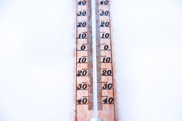 Thermometer on snow with low temperatures in celsius or fahrenheit in winter.