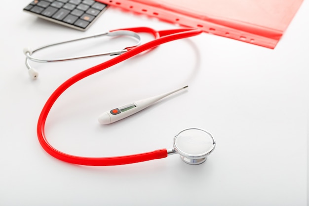 Thermometer, stethoscope and medical documents on table