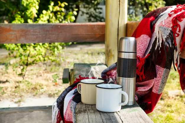 Thermos with hot tea on wooden table.