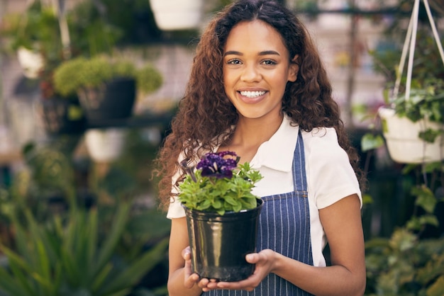 これらは私の誇りと喜びです。鉢植えの植物を持っている若い花のビジネスオーナーのショット。