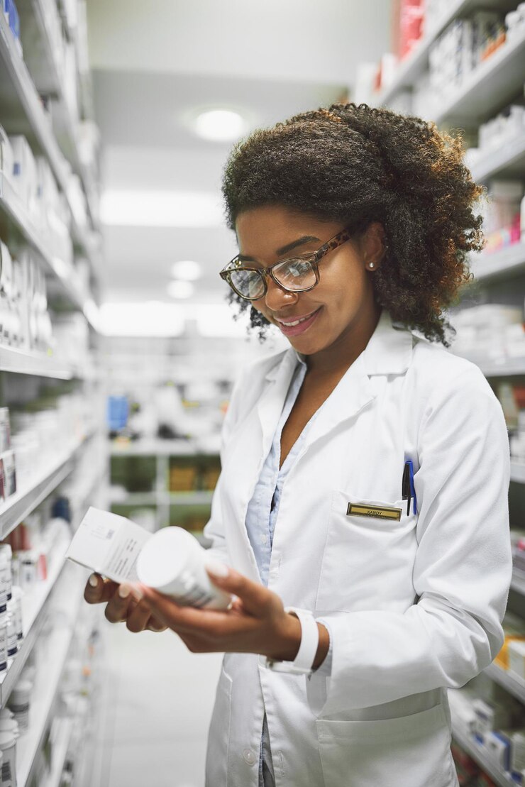 Photo these two go together well shot of a cheerful young female pharmacist holding two different types of medication in each hand in a pharmacy