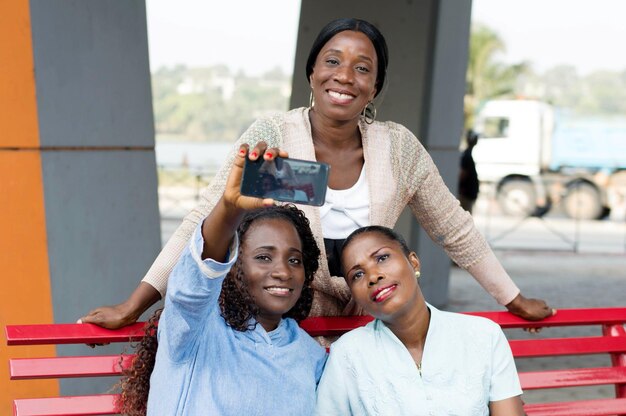 these young women sitting on a bench are photographed with a cell phone