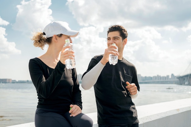 彼らはペットボトルからきれいな水を飲みます人々のアスリートは喜んでトレーニングの準備をします