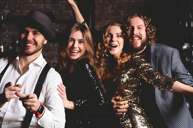 They love dancing. Group of beautiful young people dancing with champagne flutes and looking happy.