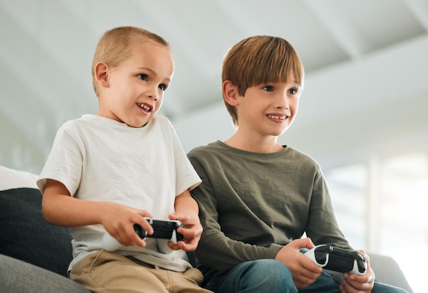 They love playing video games. Shot of two little brothers playing video games at home.