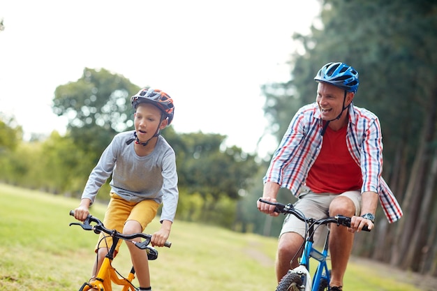 彼らはお互いにレースをするのが大好きです公園で自転車に乗る父と息子のショット