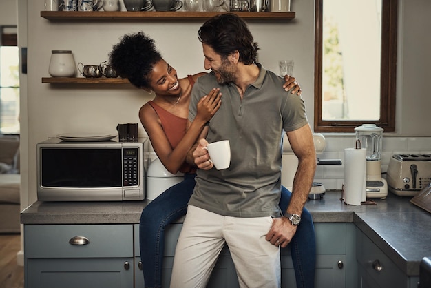 Foto sono reciprocamente felici ripresa ritagliata di una giovane coppia affettuosa che si sorride mentre trascorre del tempo di qualità nella loro cucina a casa