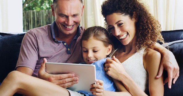 Foto sono una famiglia felice e felice foto di una bambina carina che usa una tavoletta digitale con sua madre e suo padre sul divano di casa