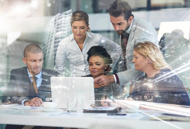 Theyre planning to take over the city Multiple exposure shot of a group of businesspeople working together on a laptop superimposed over a cityscape