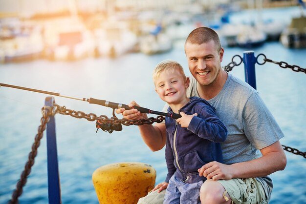 彼らは共通の趣味を持っています父と彼の小さな男の子が港で一緒に釣りをしている肖像画