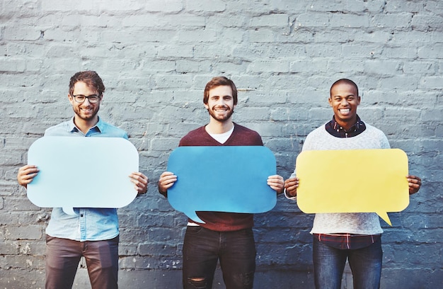 Photo theyve got some thoughts to share portrait of a group of young men holding speech bubbles against a brick wall