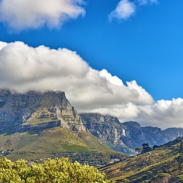 Thick clouds rolling over table mountain cape town with copyspace cloud shadows passing rocky terrain on sunny day beautiful peaceful nature in harmony with soothing view of plants and landscape