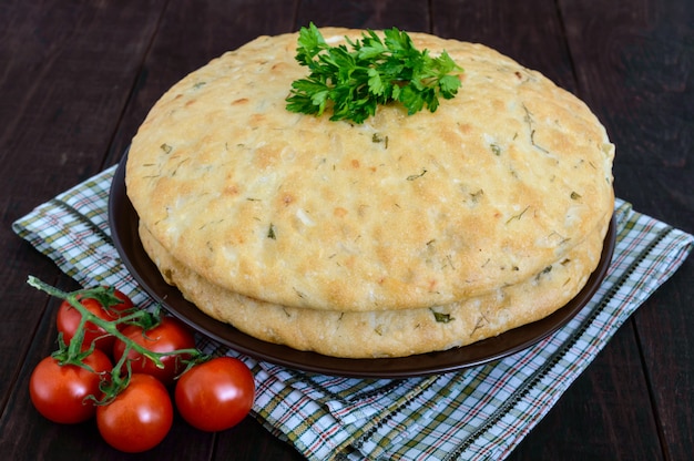 Un grosso flapjack - pane pita con verdure su uno sfondo di legno scuro. un piatto asiatico tradizionale.