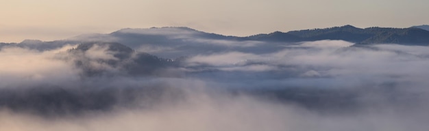 濃い霧が山を覆い、トップビューのバナーの背景