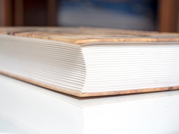 A thick and heavy closed book lies on a white surface in the house. The concept of learning and knowledge