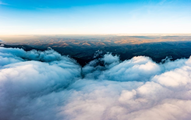 Thick layer of white clouds above mountains at sunrise