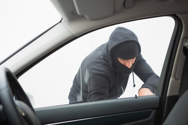 Thief breaking into car with screwdriver 