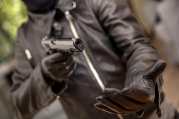 Foto mano guantata del ladro che tiene una pistola che punta la vista del primo piano concetto di rapina a mano armata