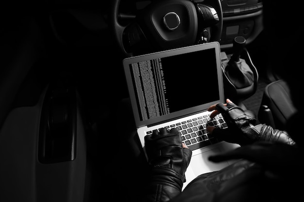 Photo thief hacking car security system with laptop