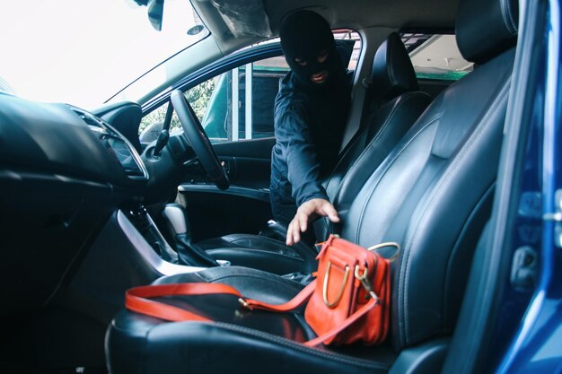 Photo a thief in a robbery mask stealing a purse bag in a car