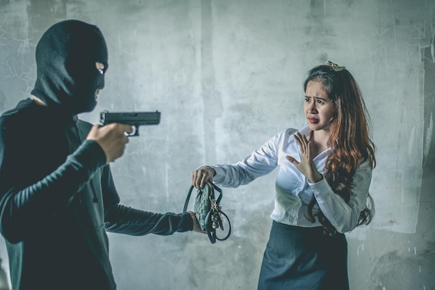 Foto un ladro che mostra la pistola a una donna.