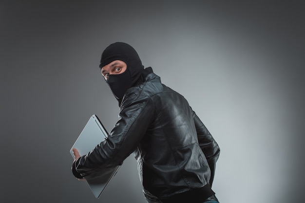 Thief stealing a laptop computer. Isolated on gray background