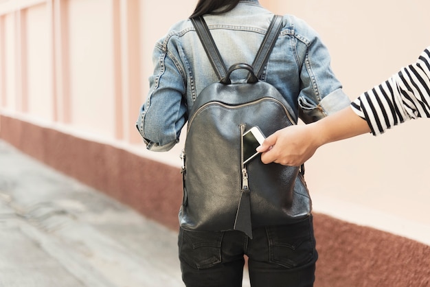 Ladro che ruba il cellulare dalla borsa del viaggiatore per strada.