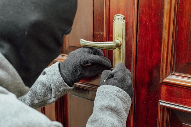 Thief tries to pick a lock to enter the house concept of security and danger of home burglary