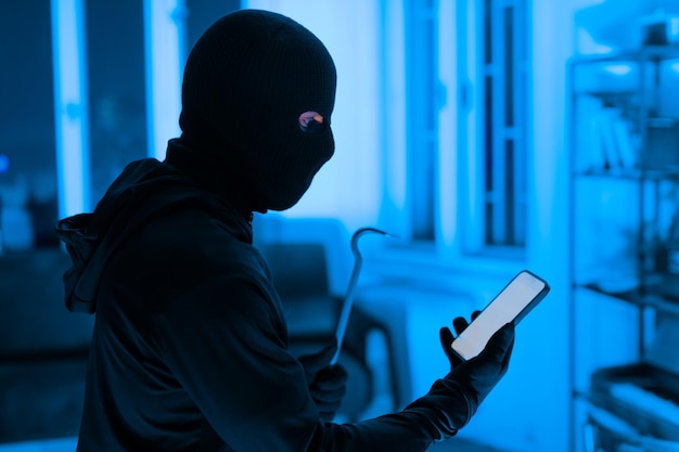 Thief using a smartphone during a breakin