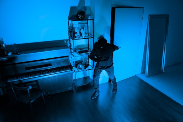 Foto un ladro con un bastone che entra in una casa sicura.