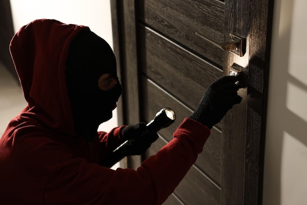 Thief with flashlight breaking foreign door39s lock in hall Burglary
