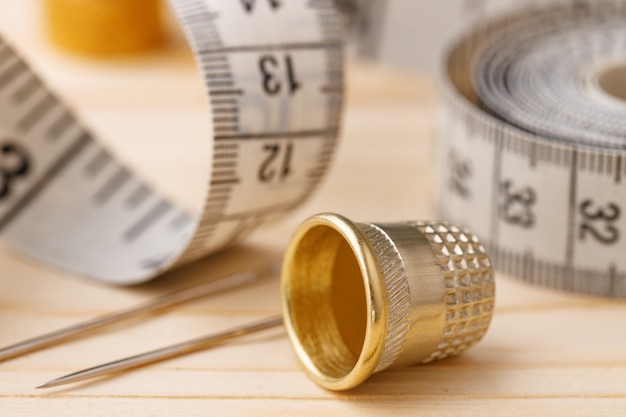 Thimble and measuring tape on wooden table