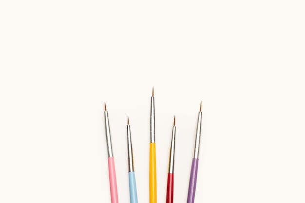 Thin artistic paintbrushes on a white background with copy space