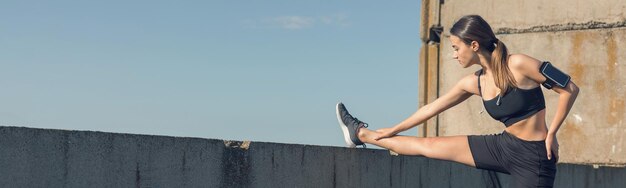 A thin athletic girl takes a break between classes on the background of beautiful sky at sunset enjoys silence and freedom