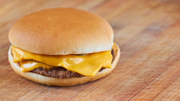 Photo thin cheeseburger or hamburger on a wooden board with diagonal lines.selective focus. copy space. wide crop