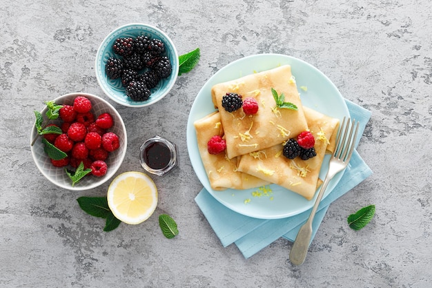 Photo thin crepes with fresh berries and lemon zest pancakes with raspberry and blackberry