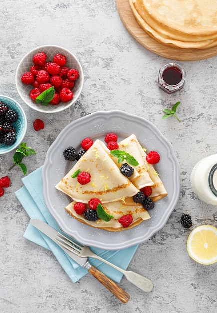 Thin crepes with fresh berries and lemon zest Pancakes with raspberry and blackberryxA