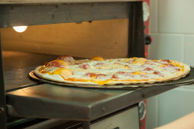 Thin delicious pizza is baked in the oven. Cooking pizza in a pizzeria.