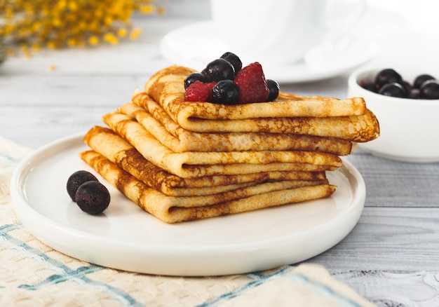 Frittelle fatte in casa sottili con frutti di bosco sul piatto