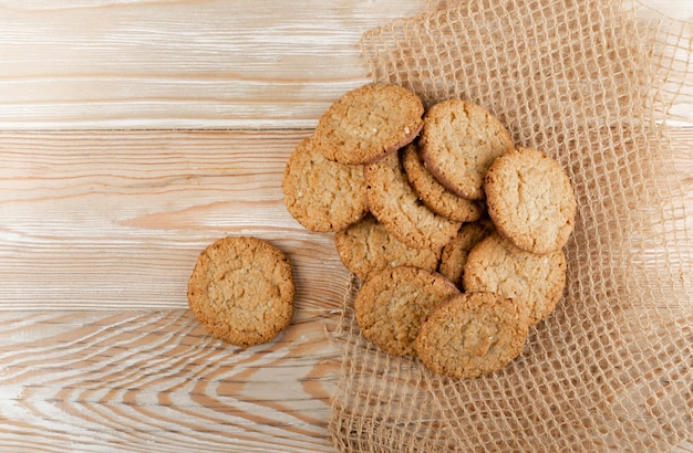 Thin oatmeal cookies or healthy cereal oat crackers with chocolate. Crispy anzac biscuit cookie with oat flakes on rustic table background top view