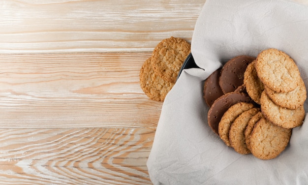 Thin oatmeal cookies or healthy cereal oat crackers with chocolate. Crispy anzac biscuit cookie with oat flakes on rustic table background top view