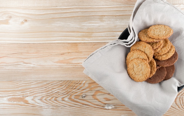 Thin oatmeal cookies or healthy cereal oat crackers with chocolate. Crispy anzac biscuit cookie with oat flakes on rustic table background top view