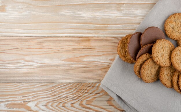 Thin oatmeal cookies or healthy cereal oat crackers with chocolate. Crispy anzac biscuit cookie with oat flakes on rustic table background top view