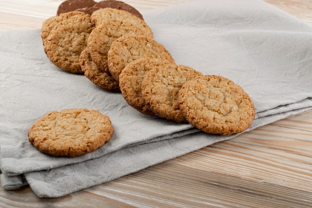 Thin oatmeal cookies or healthy cereal oat crackers with chocolate. Crispy anzac biscuit cookie with oat flakes on rustic table background