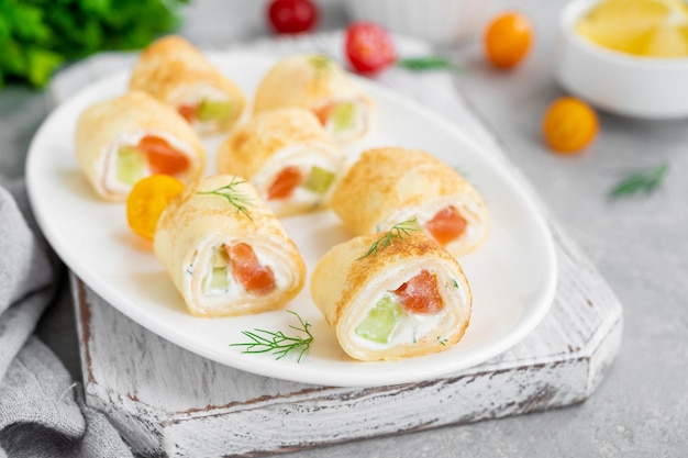 Thin pancake rolls or crepes with smoked salmon cream cheese cucumber and dill Selective focus