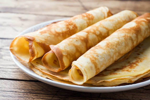 Thin pancakes on a plate. Wooden background. Close up.