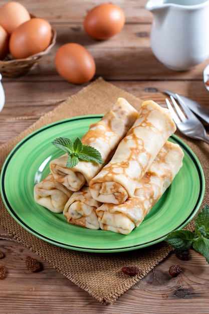 Thin pancakes with cottage cheese and raisins on wooden table Healthy traditional breakfast concept