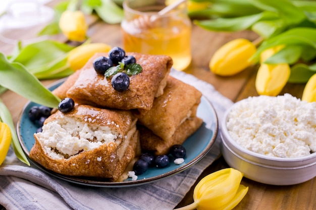 カッテージチーズとイチゴの薄いパンケーキ。健康的な伝統的な朝食のコンセプトです。春の伝統的なロシアのカーニバル、マスレニツァを焼きます。コピースペース。