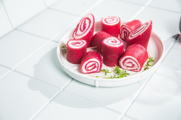 Thin red pancakes. Rolls of beetroot pancakes with cream cheese