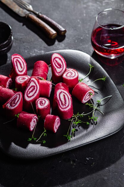 Thin red pancakes. Rolls of beetroot pancakes with cream cheese